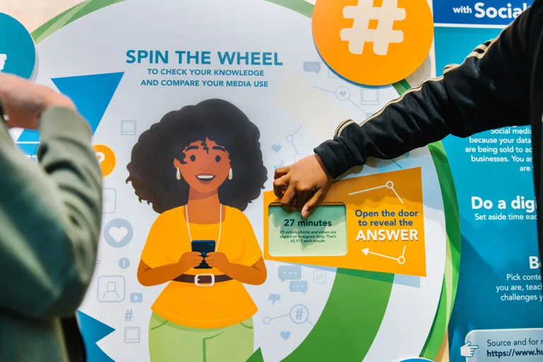 Students using Daily Media Use spinning wheel activity at Wonder Media Exhibit